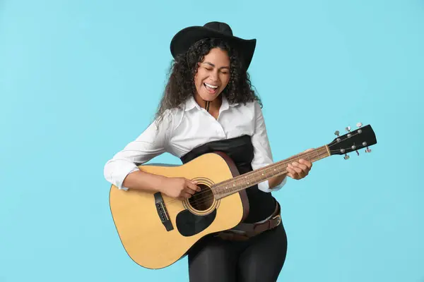 stock image African-American cowgirl playing guitar on blue background