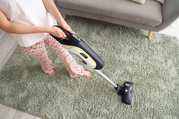 Woman cleaning soft carpet with vacuum cleaner at home, closeup