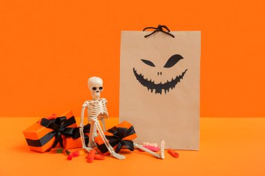 Renkli arkaplanda Cadılar Bayramı için kağıt alışveriş torbası, hediye kutusu, dekor ve şeker kompozisyonu