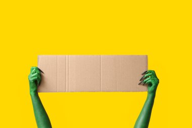 Sarı arka planda boş karton çarşaf olan cadının yeşil elleri. Cadılar Bayramı