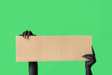 Yeşil zemin üzerinde boş karton çarşaf olan cadının kara elleri. Cadılar Bayramı