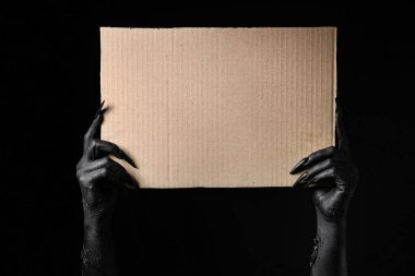 Karanlık arka planda boş karton çarşaf olan cadının kara elleri. Cadılar Bayramı