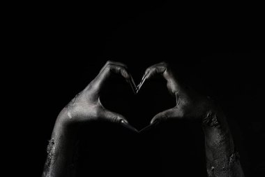 Black hands of witch showing heart gesture on dark background. Halloween celebration clipart