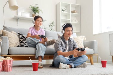 Erkek kardeşi ve kulaklığı evde video oyunu oynuyor.