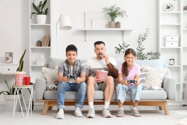 Patlamış mısırlı baba ve çocukları evde video oyunu oynuyorlar.