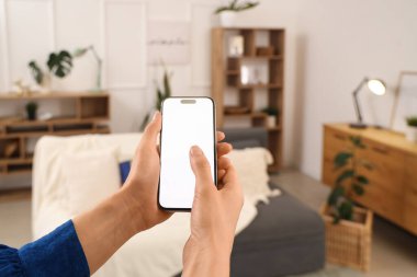 Oturma odasında boş cep telefonu kullanan kadın, yakın plan.