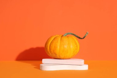 Turuncu arka planda taze balkabağı olan dekoratif podyumlar