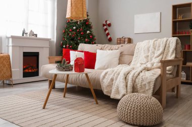 Beyaz kanepesi, sehpası, Noel ağacı ve şöminesi olan festival salonu.