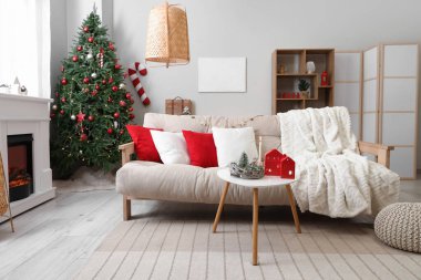 Beyaz kanepesi, sehpası, Noel ağacı ve şöminesi olan festival salonu.