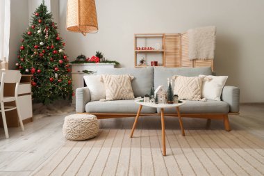 Gri kanepesi, kahve masası ve Noel ağacı olan şenlikli oturma odasının içinde.