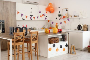 Cadılar Bayramı partisi için dekore edilmiş modern mutfağın içi balkabakları, çelenkler ve kelime BOO ile süslenmiş.