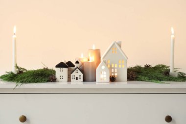 Ev şeklinde tutucuları olan mumlar yakmak ve ışık duvarının yanındaki klozette Noel dalları