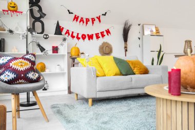 Cadılar Bayramı için dekore edilmiş oturma odasının içi kanepe ve raf ünitesi ile dolu.