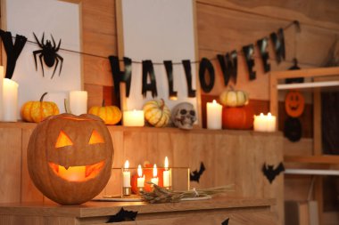 Cadılar Bayramı için dekore edilmiş oturma odasının içinde yanan mumlar ve balkabakları var.