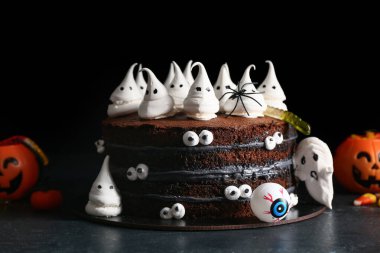 Siyah arka planda hayaletler, gözler ve jelibon solucanları olan lezzetli Cadılar Bayramı pastası.