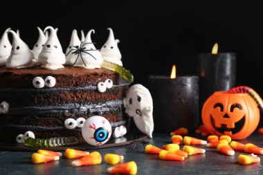 Tatlı Cadılar Bayramı pastası, siyah arka planda hayaletler, gözler ve şekerli mısır.