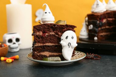 Sarı arka planda siyah masada hayaletler ve jelibon solucanları olan lezzetli bir Cadılar Bayramı pastası.