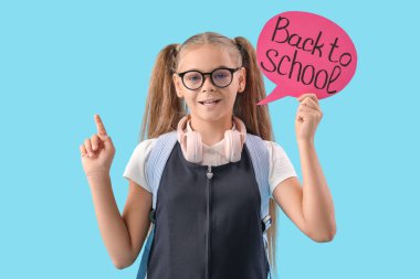 Okul üniformalı, elinde konuşma balonuyla okula geri dönen ve mavi arkaplanı işaret eden sevimli küçük bir kız.