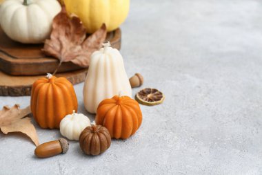 Işık masasında sonbahar mumları, balkabakları ve dekoru olan kompozisyon