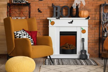 Cadılar Bayramı için dekore edilmiş oturma odasının içinde şömine ve koltuk var.