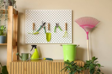 Atölyedeki bej duvarda bahçe aletleri olan Peg tahtası