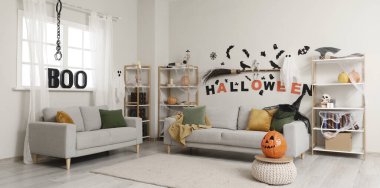 Cadılar Bayramı süslemeleri ve gri koltukları olan oturma odasının içinde.