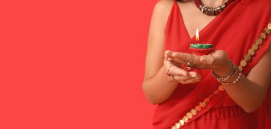 Sari 'deki Hintli kadın kırmızı arka planda diya lambası tutuyor ve mesaj için yeri var. Divaly kutlaması