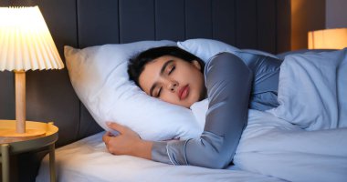 Beautiful young woman sleeping in bedroom at night