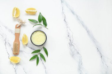 Beyaz arka planda bir kase limonlu vücut fırçası ve masaj fırçası.