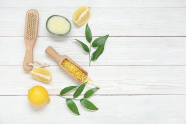 Bir kase limonlu vücut fırçası ve beyaz ahşap arka planda deniz tuzu.
