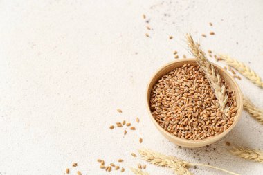 Tahta kase, buğday kulakları ve tahıllar beyaz masada.