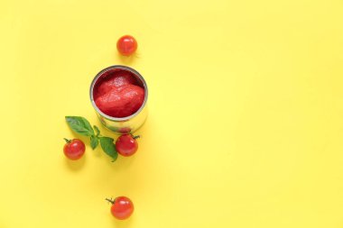 Sarı arka planda domatesli teneke kutu.