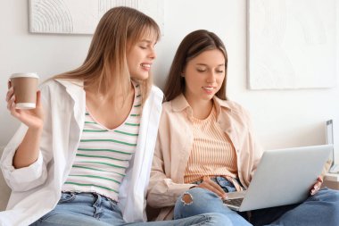 Yurt odasında dizüstü bilgisayarla çalışan kız öğrenciler.