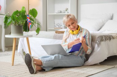 Yetişkin kadın yatak odasında İngilizce öğreniyor.