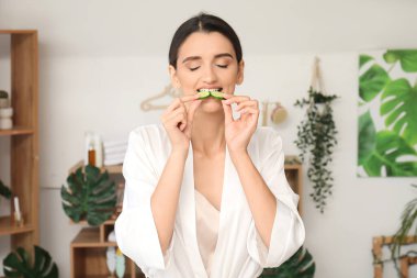 Arka planda salatalık yiyen genç bir kadın.