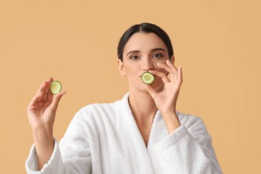 Bej arka planda salatalık dilimleri olan genç bir kadın.