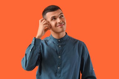 Turuncu arka planda düşünceli bir genç adam.