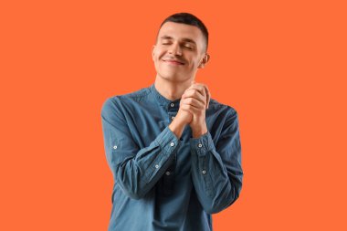 Turuncu arka plandaki mutlu genç adam.