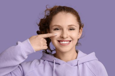 Mor arka planda burnunu gösteren güzel bir genç kızın portresi.