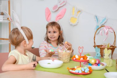 Paskalya yumurtalı küçük çocuklar mutfakta yemek yiyorlar.