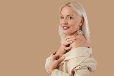 Güzel küpeli, kahverengi yüzüklü, modaya uygun olgun bir kadın.