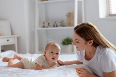 Güzel, genç, mutlu bir anne ve küçük sevimli bir bebek yatak odasında yatıyor.