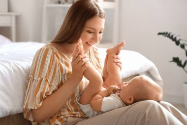 Güzel, genç, mutlu bir anne ve yatak odasında çıngırağı olan sevimli bir bebek.