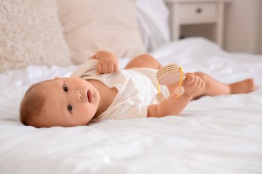 Evde, yatakta çıngıraklı şirin bir bebek yatıyor.