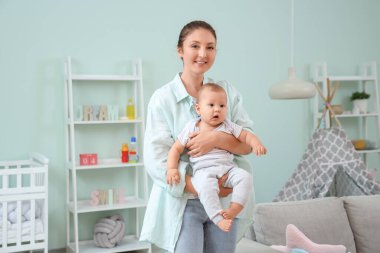 Güzel, genç, mutlu bir anne. Evdeki çocuk odasında küçük sevimli bir bebek.