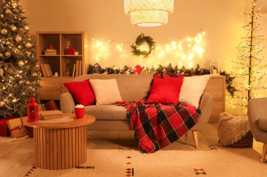 Geceleri tatil için süslenmiş kanepesi ve Noel ağacı olan rahat bir oturma odası.