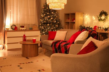 Geceleri tatil için süslenmiş kanepesi ve Noel ağacı olan rahat bir oturma odası.