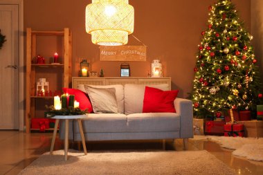 Geceleri Noel ağacının yanında kanepe ve hediye kutuları olan rahat bir oturma odası.