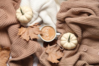 Bir fincan lezzetli balkabağı kahvesi, sonbahar yaprakları ve sıcak süveterler, üst manzara.