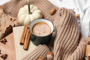 Evde sonbahar süslemeleri, kitaplar ve sıcak süveter olan lezzetli balkabağı kahvesi.